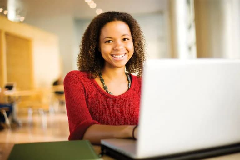 Woman smiling towards camera while using a computer